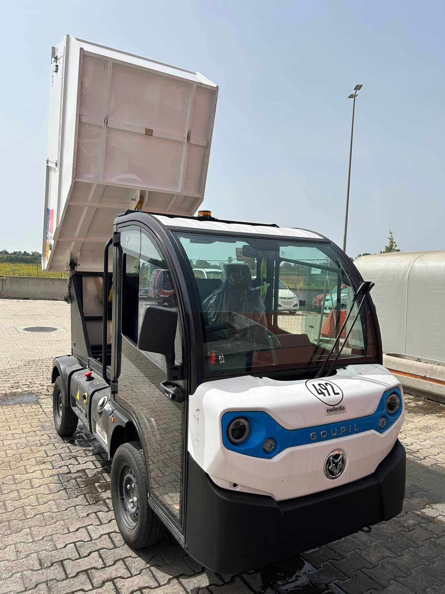 Un piccolo autocarro con cassone ribaltabile elettrico è parcheggiato in un parcheggio.