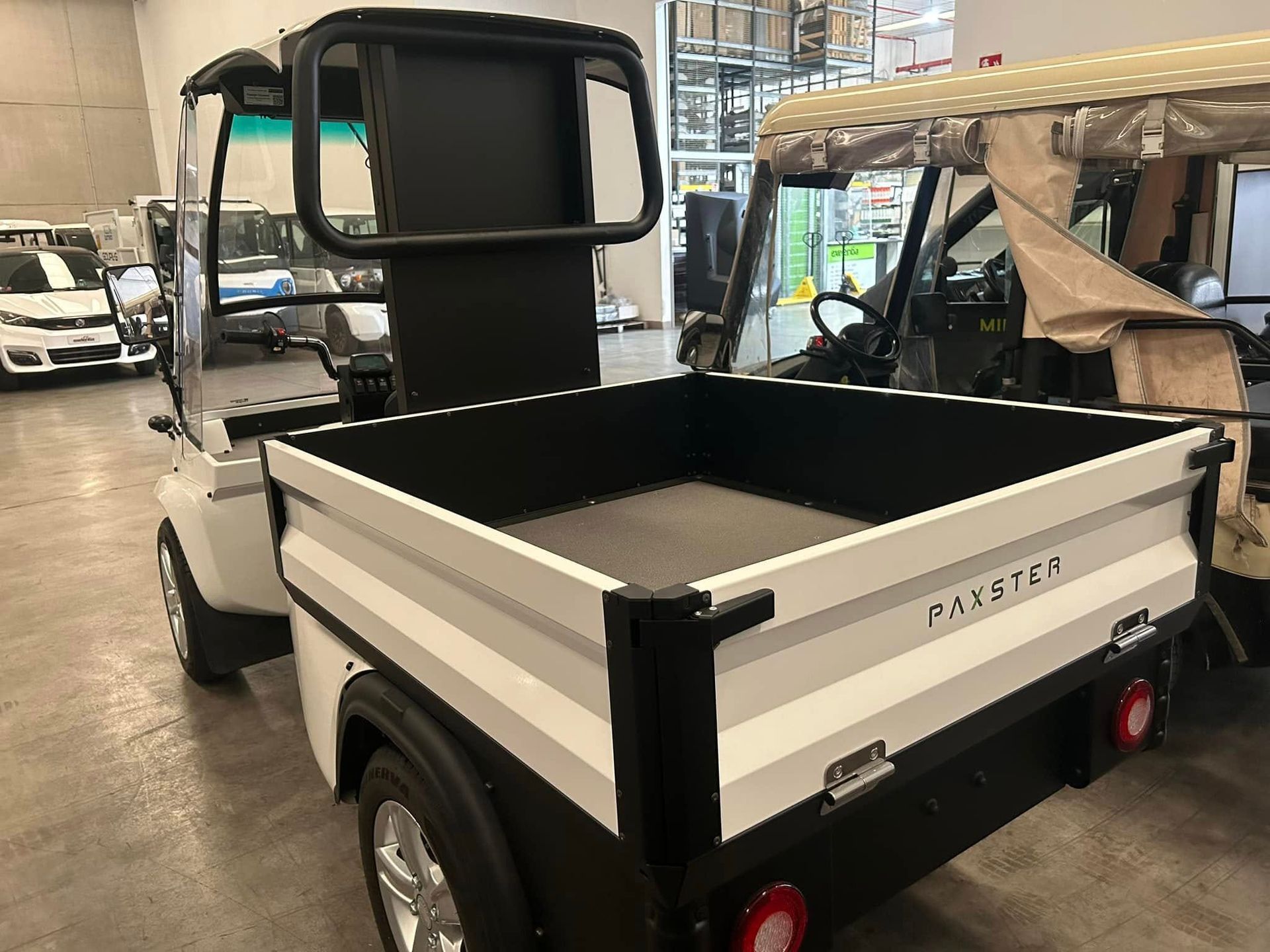 Un golf cart bianco con cassone è parcheggiato in un garage.