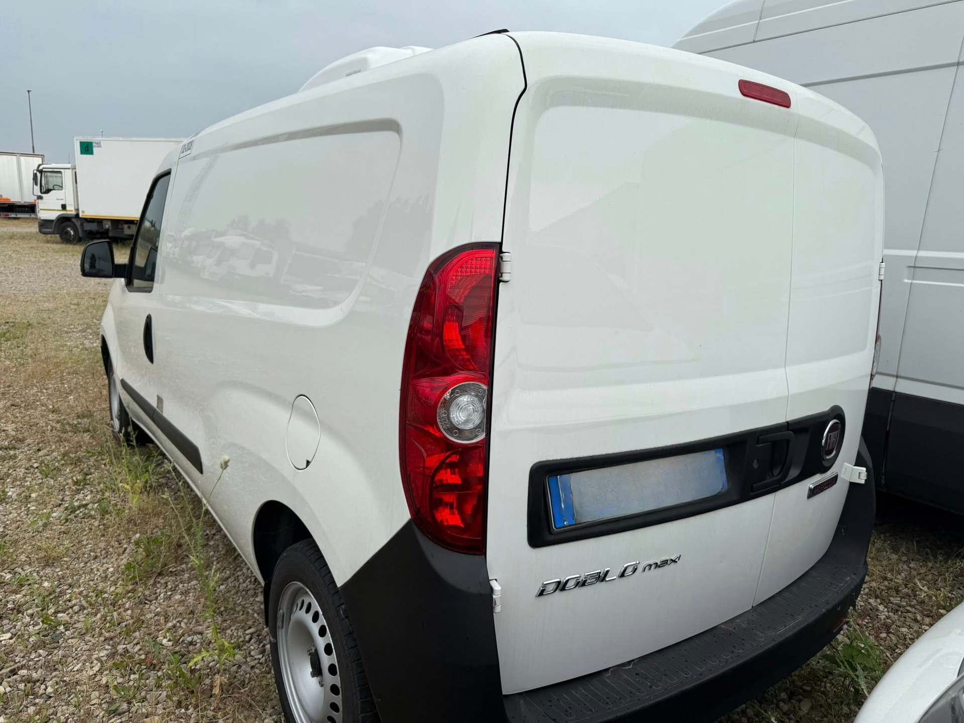 Un furgone bianco è parcheggiato in uno spiazzo ghiaioso.