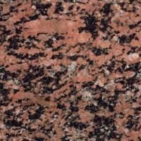 Et nærbillede af en bordplade i rød granit med sorte pletter.