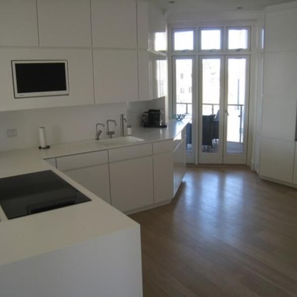 Et køkken med hvide skabe og et fladskærms-tv