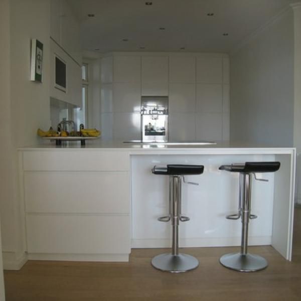 Et køkken med to barstole og et køleskab