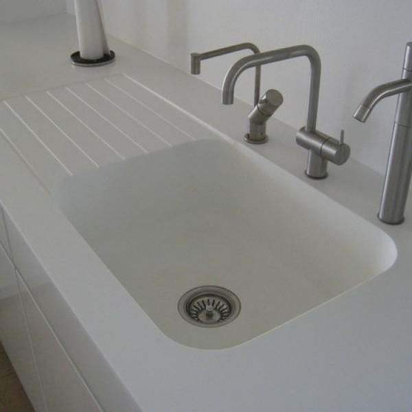 En køkkenvask med to vandhaner og et afløb.