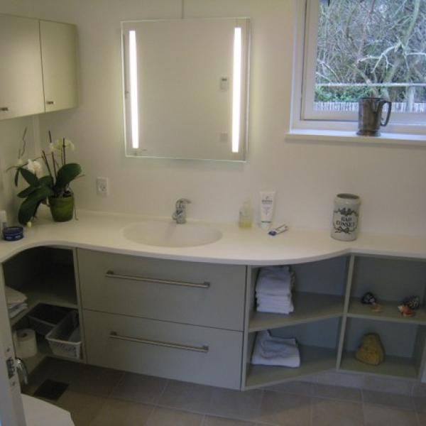 Et badeværelse med en vask, et spejl og et vindue