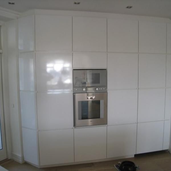 Et køkken med hvide skabe og en rustfri ovn