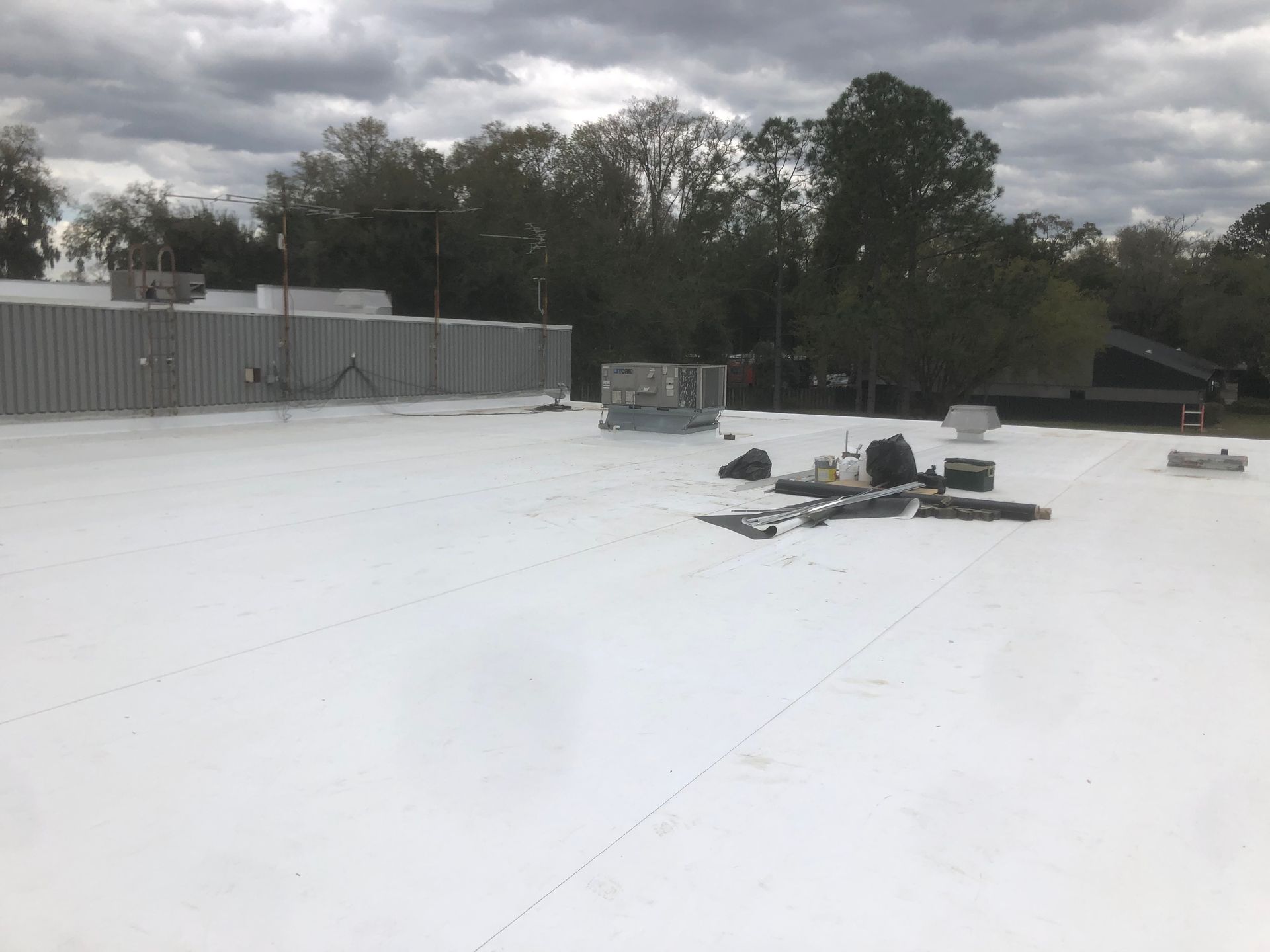 A high view of a flat roof of a commercial building. The Roof's floor is white, with  electric systems installed.