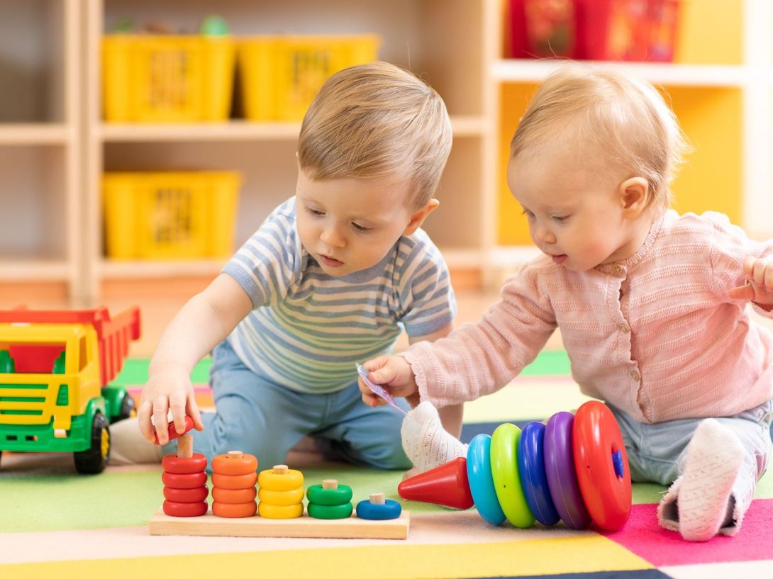 A boy and a girl are playing with toys on the floor.