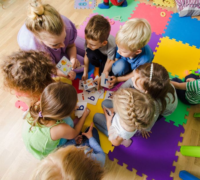 A group of children are sitting on the floor playing with cards