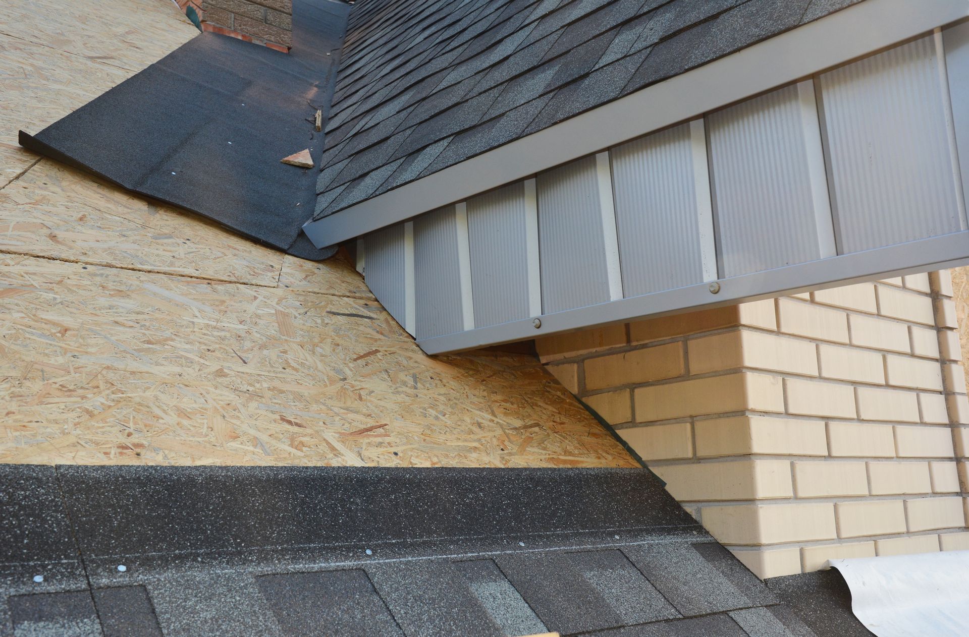 Roof construction detail showing shingles, plywood, and a brick chimney.