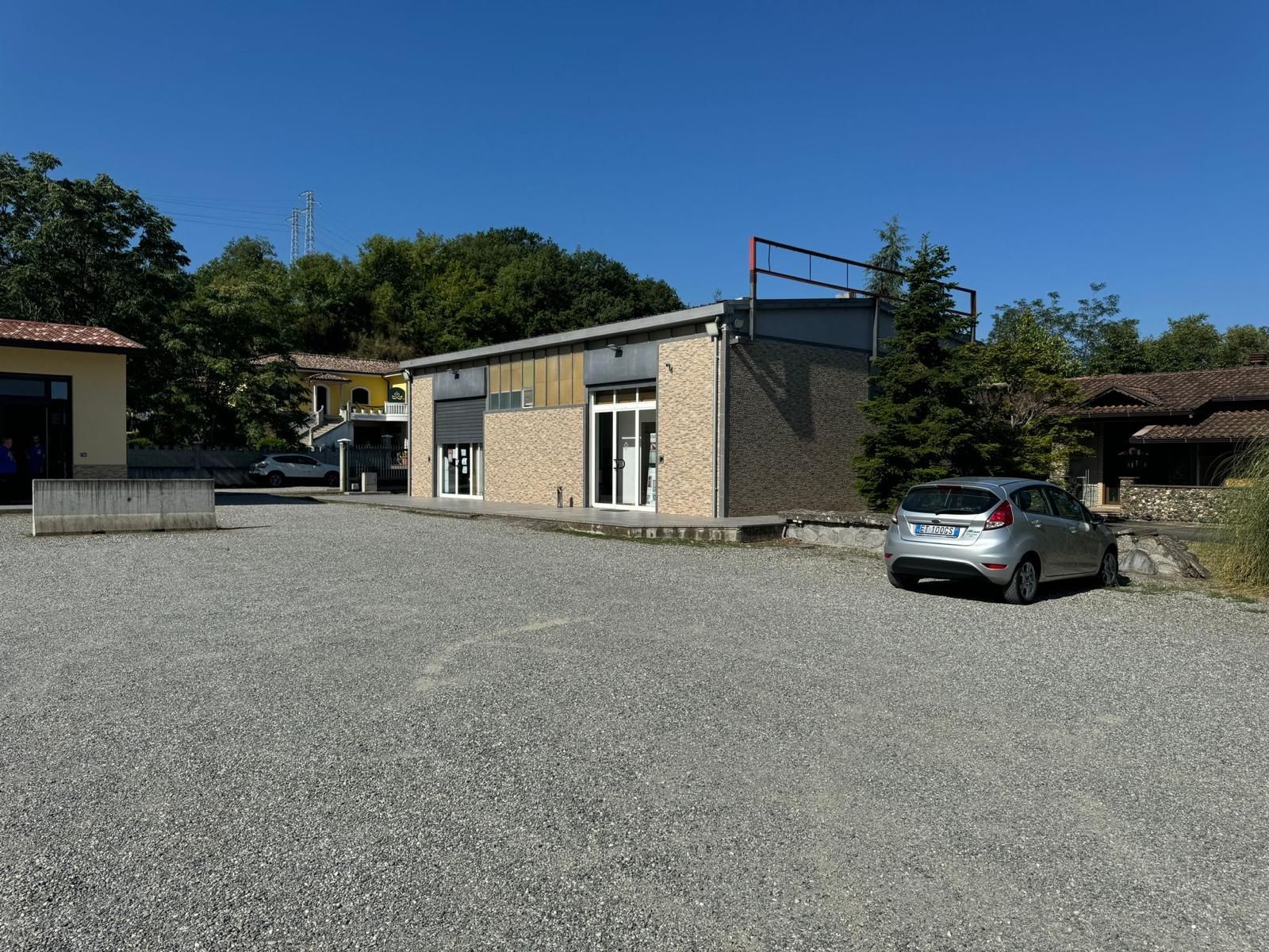 Un'auto è parcheggiata in un piazzale di ghiaia davanti a un edificio