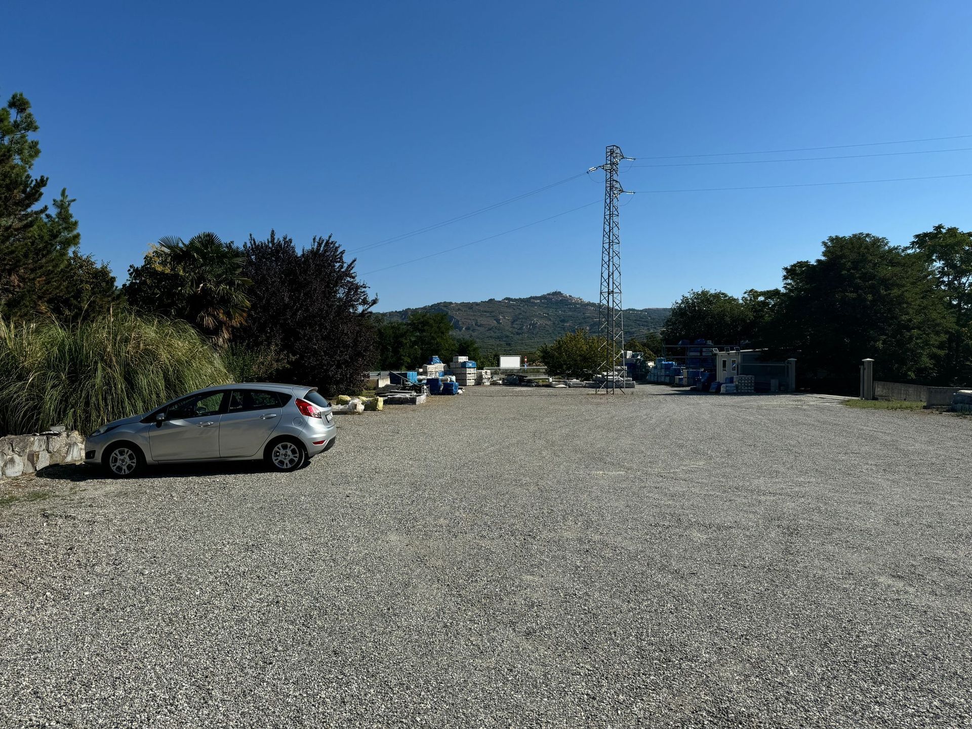 Un'auto è parcheggiata in un parcheggio ghiaioso.