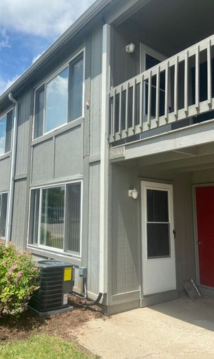 Gray apartment building exterior with balcony and red door.