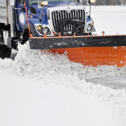 Snowplow clearing snow with an orange plow blade on a snowy street