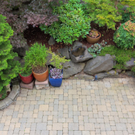 Backyard patio with potted plants and a rock garden beside a stone path