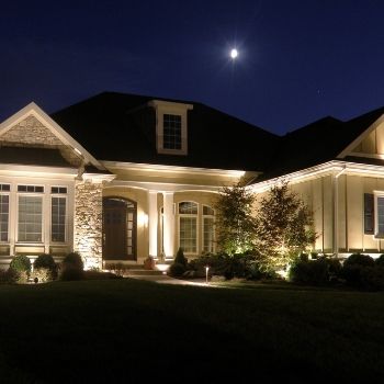 Illuminated suburban house at night with a bright moon overhead