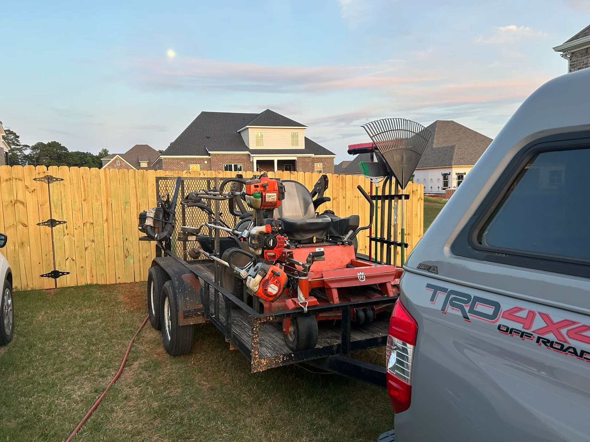 A truck is towing a trailer with a lawn mower on it.