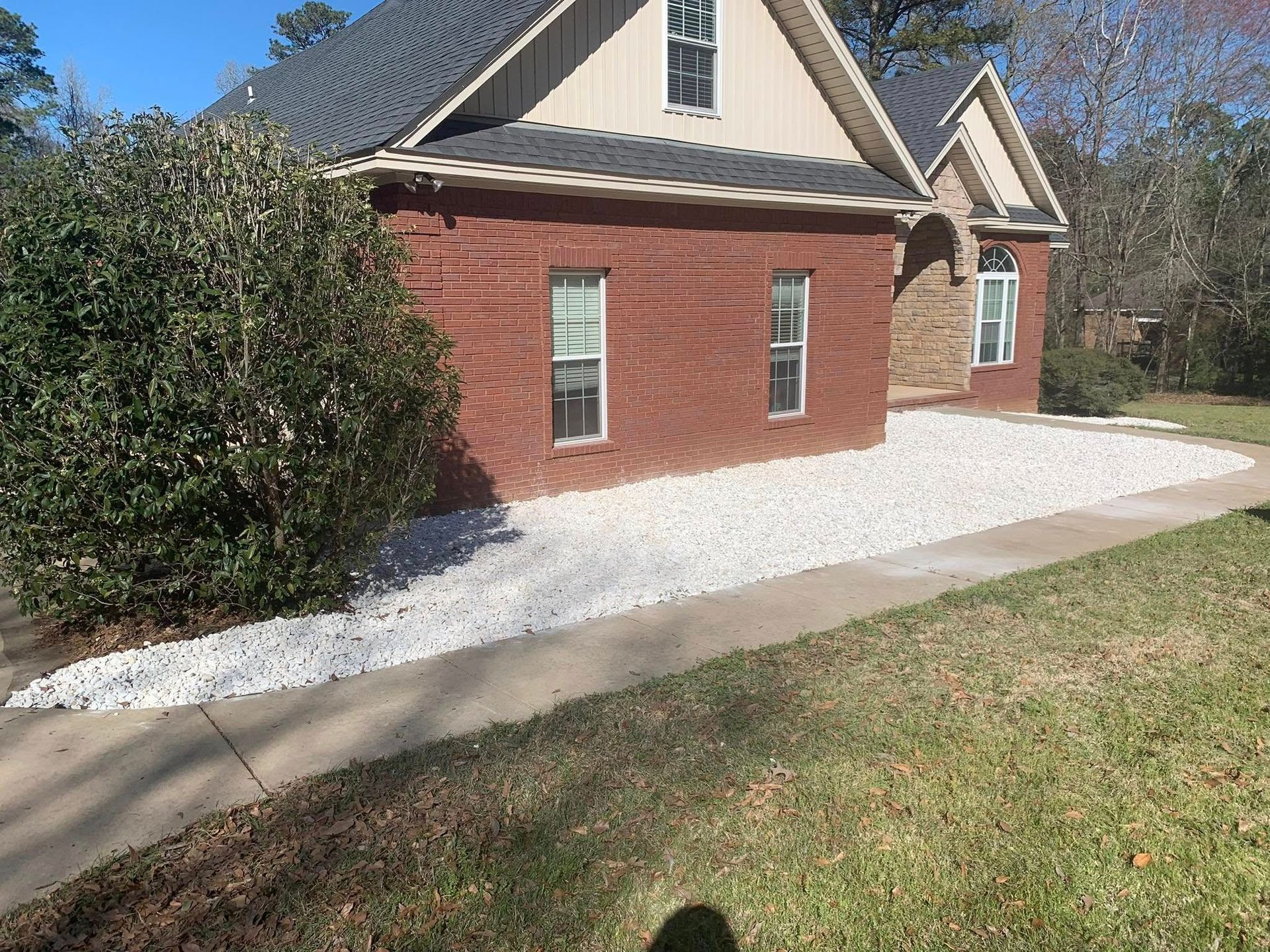 A brick house with a rock landscape in front of it.