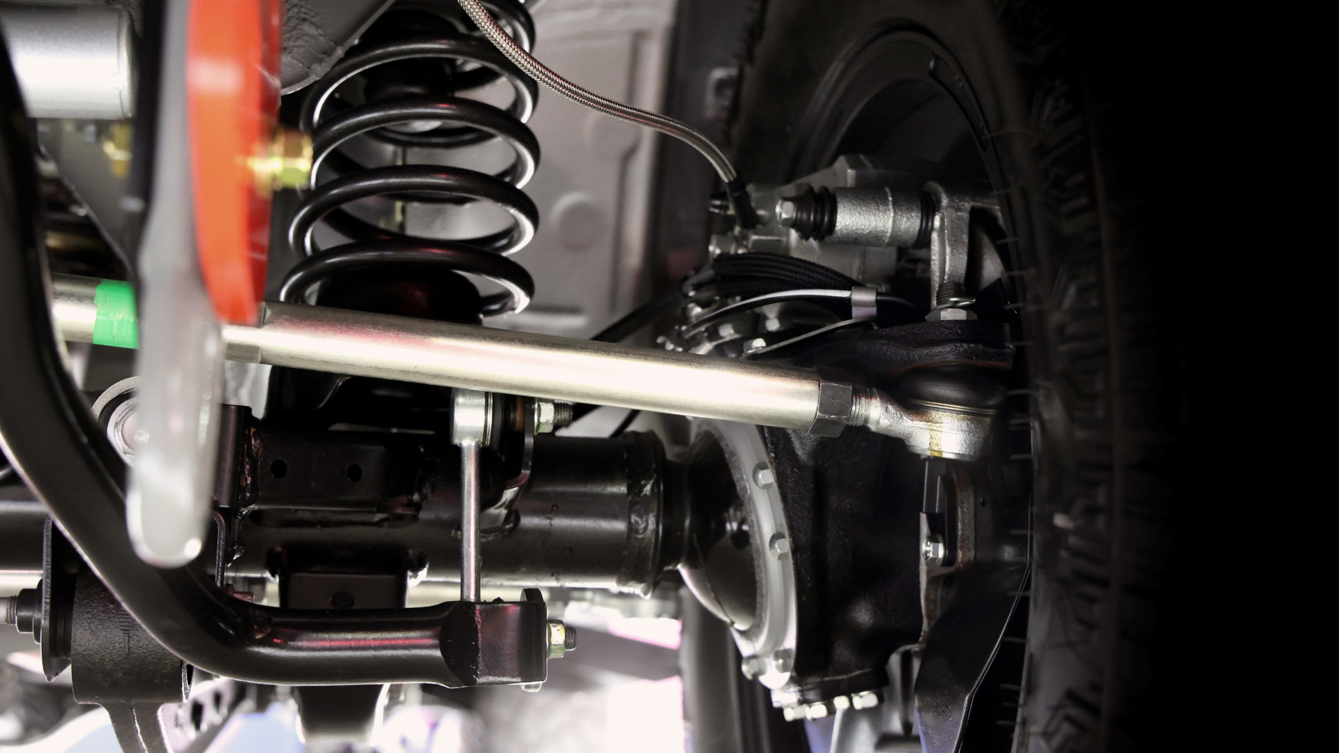 Undercarriage of a vehicle with suspension components, including a coil spring and tie rod.