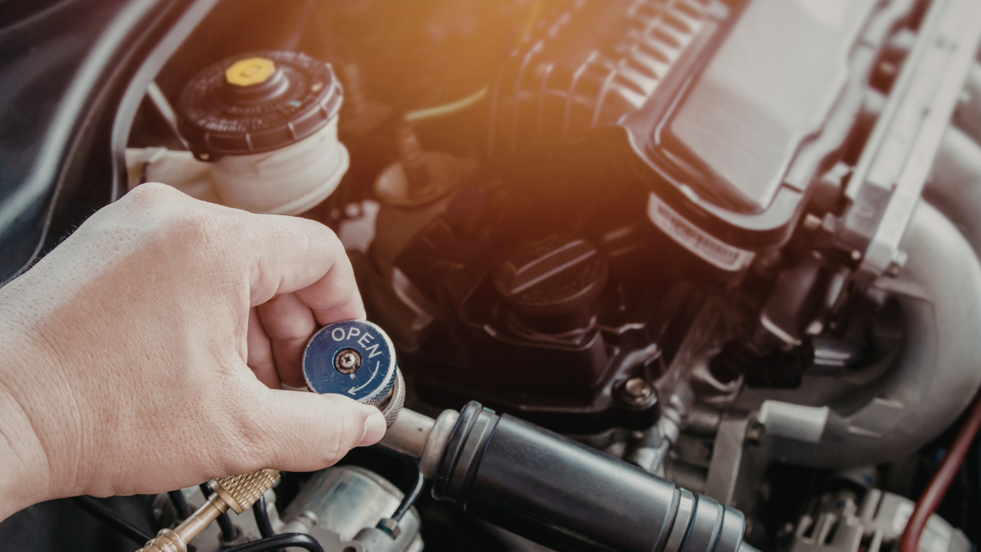 Hand holding a blue gauge in front of a car engine.