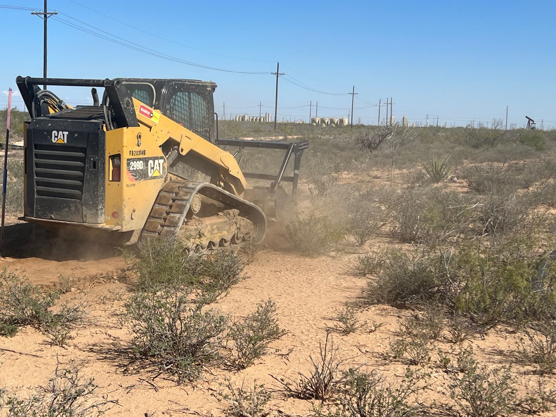 A yellow and black cat bulldozer is driving through a dirt field.