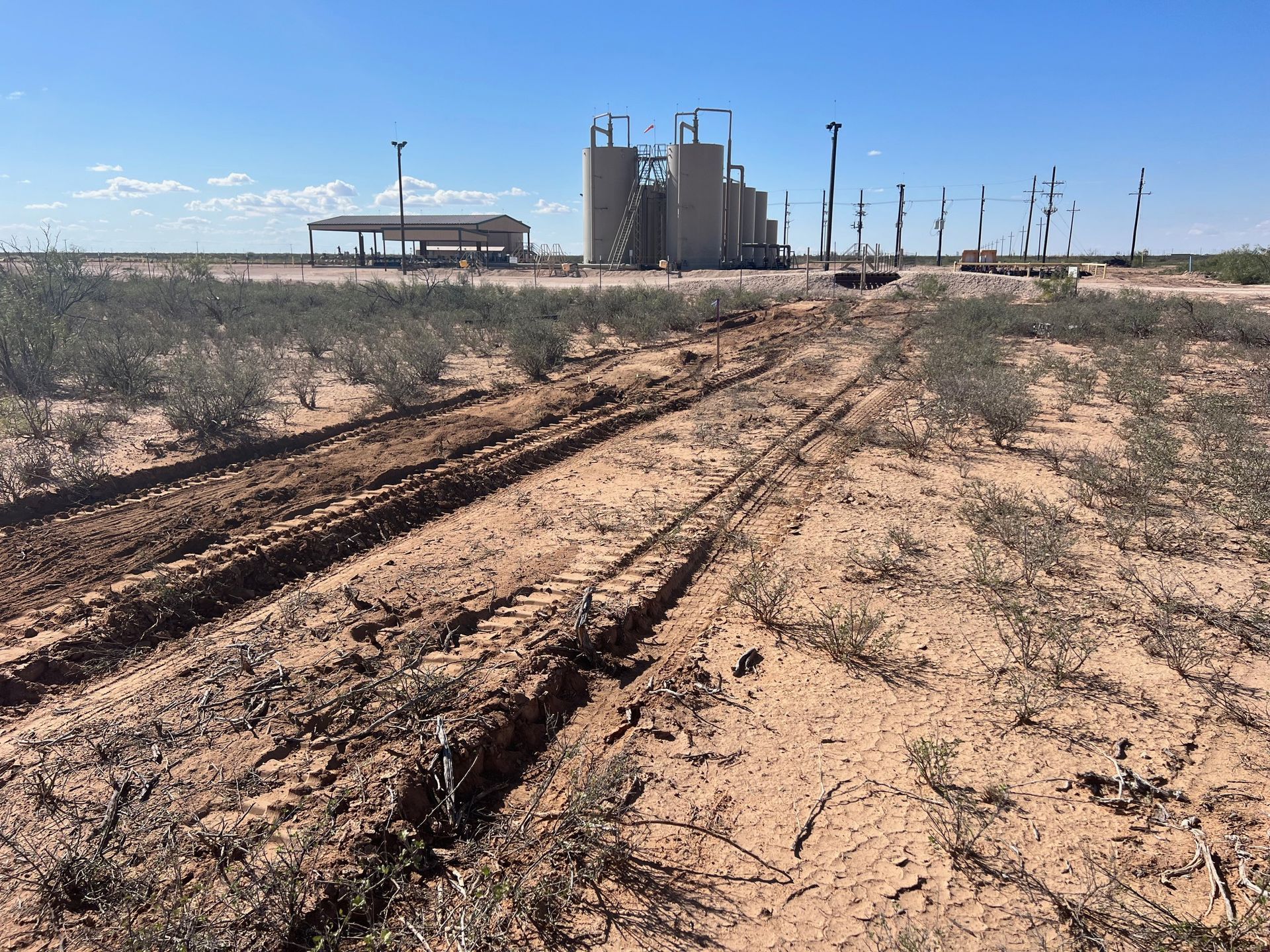 A dirt road leading to a factory in the desert