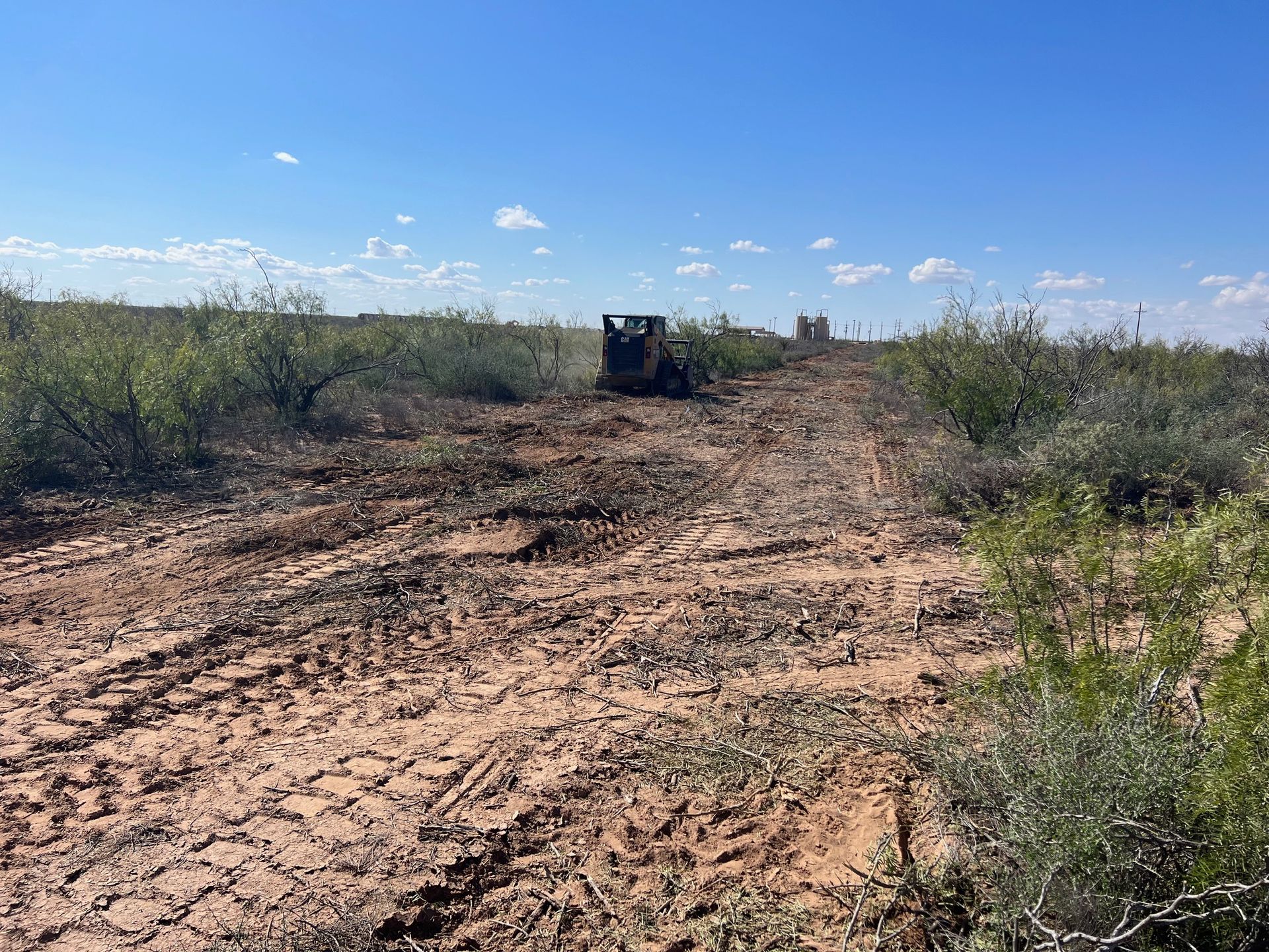 A bulldozer is driving down a dirt road in a field.