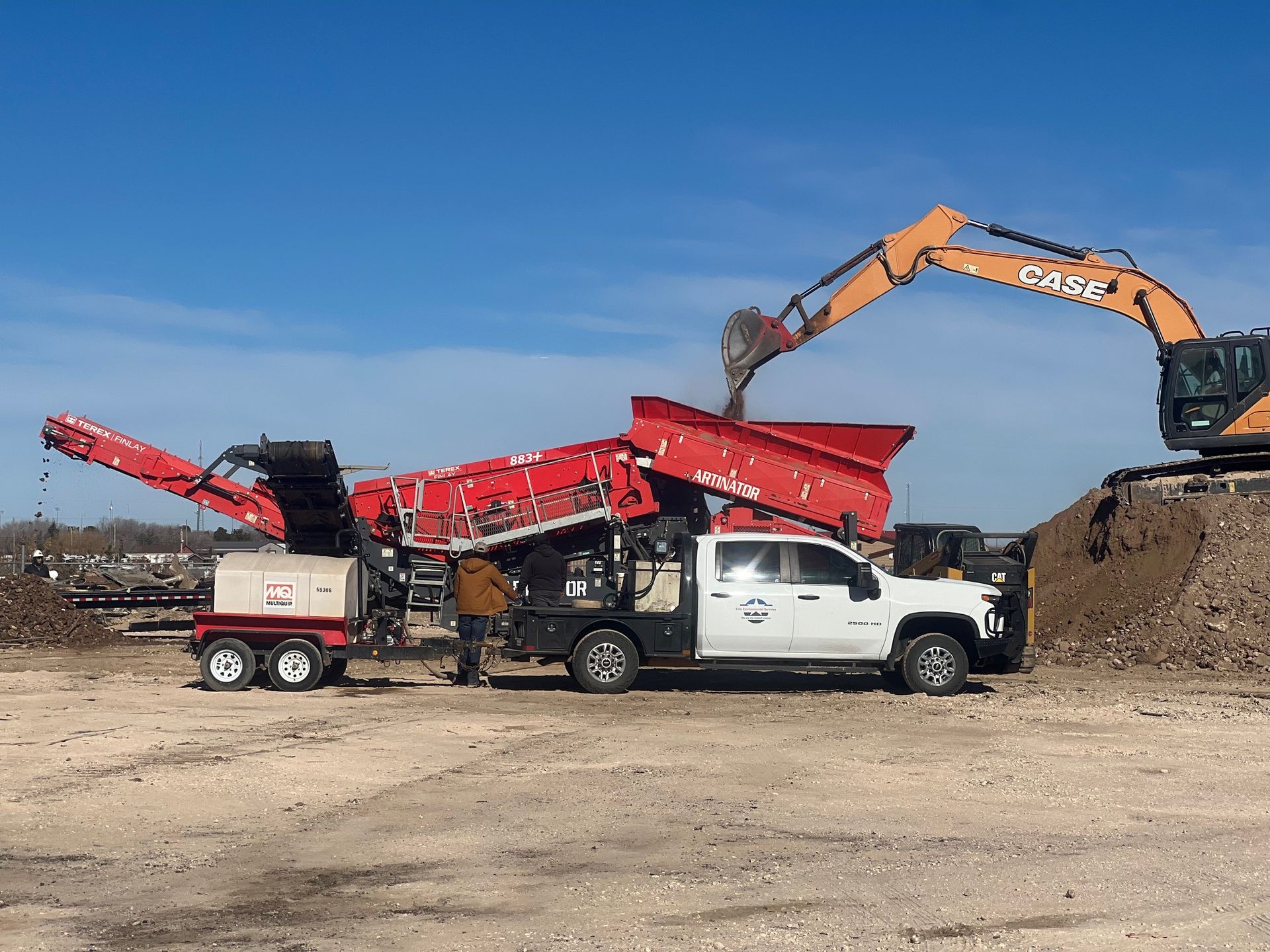 A white truck is parked in a dirt field next to an excavator.