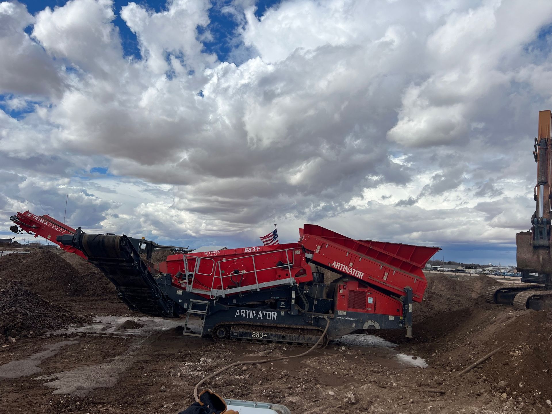 A red and black machine is sitting in the middle of a dirt field.