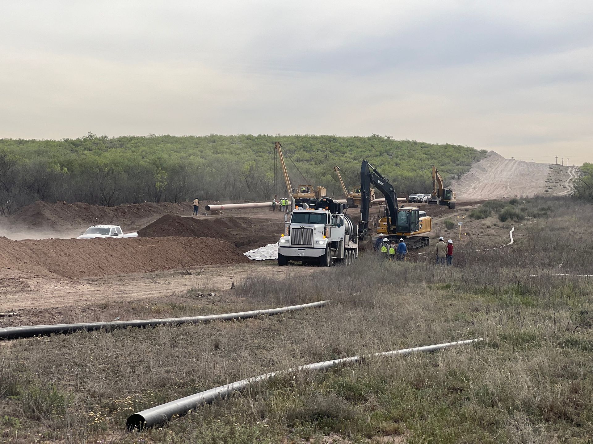 A truck is driving down a dirt road next to a construction site.