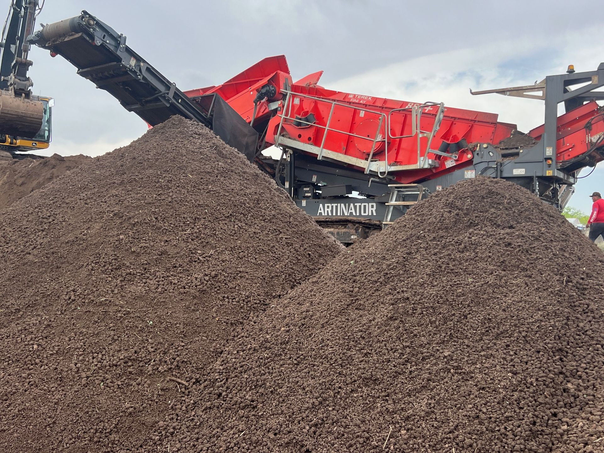 A large pile of dirt is being processed by a machine.