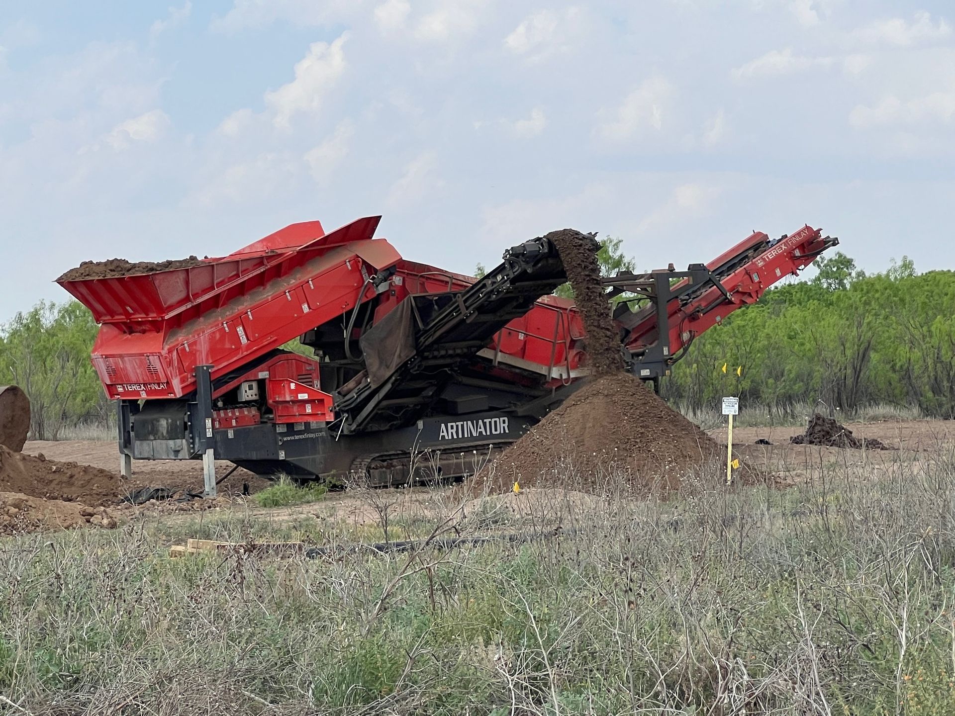 A large red machine is sitting in the middle of a field.