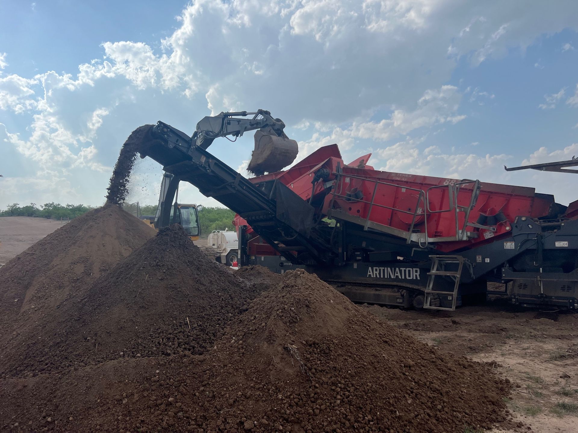A pile of dirt is being loaded into a machine.