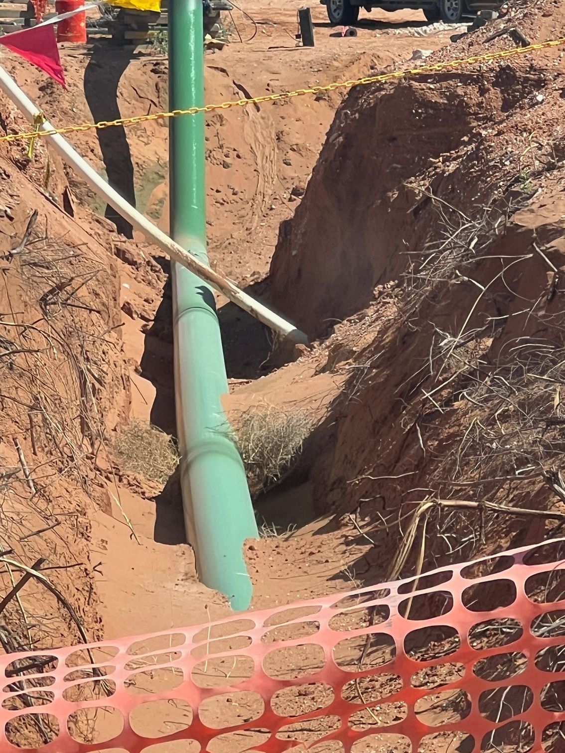 A green pipe is being installed in a hole in the ground.