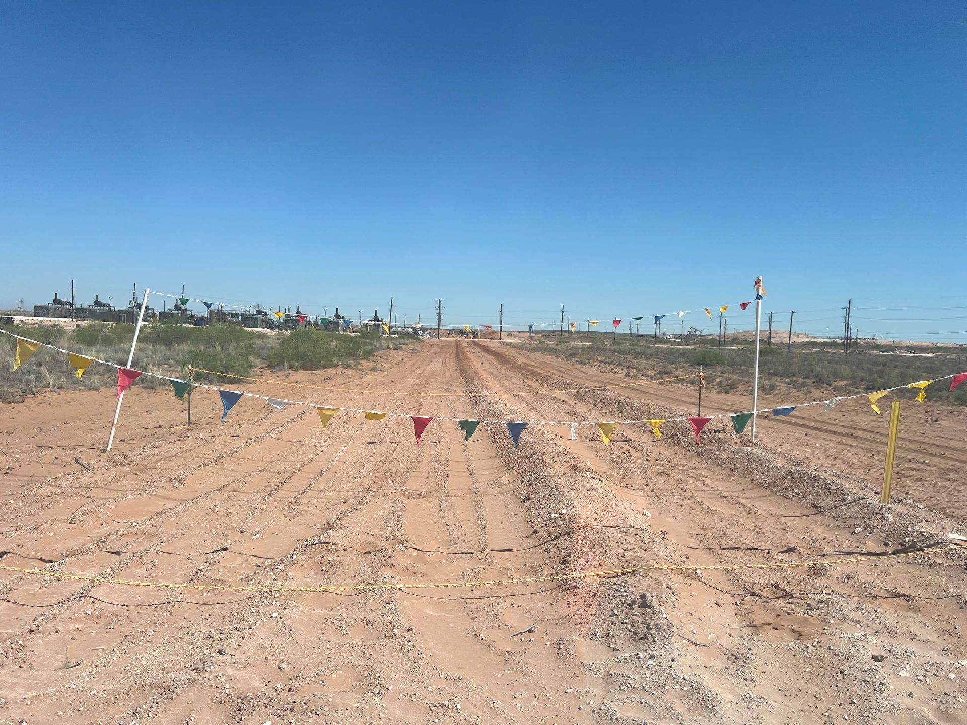 A dirt road with flags on the side of it
