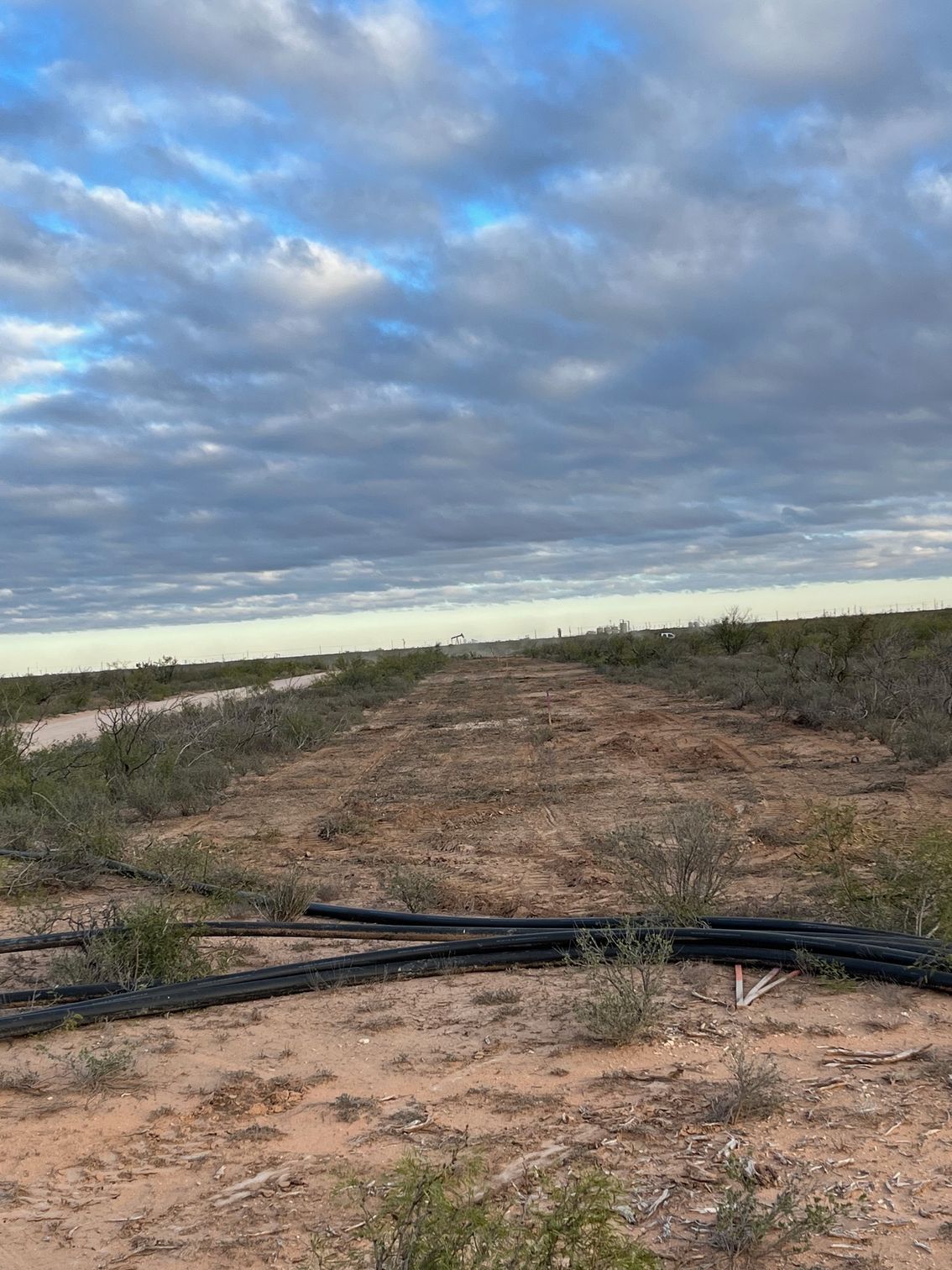 A dirt field with a blue sky and clouds in the background.