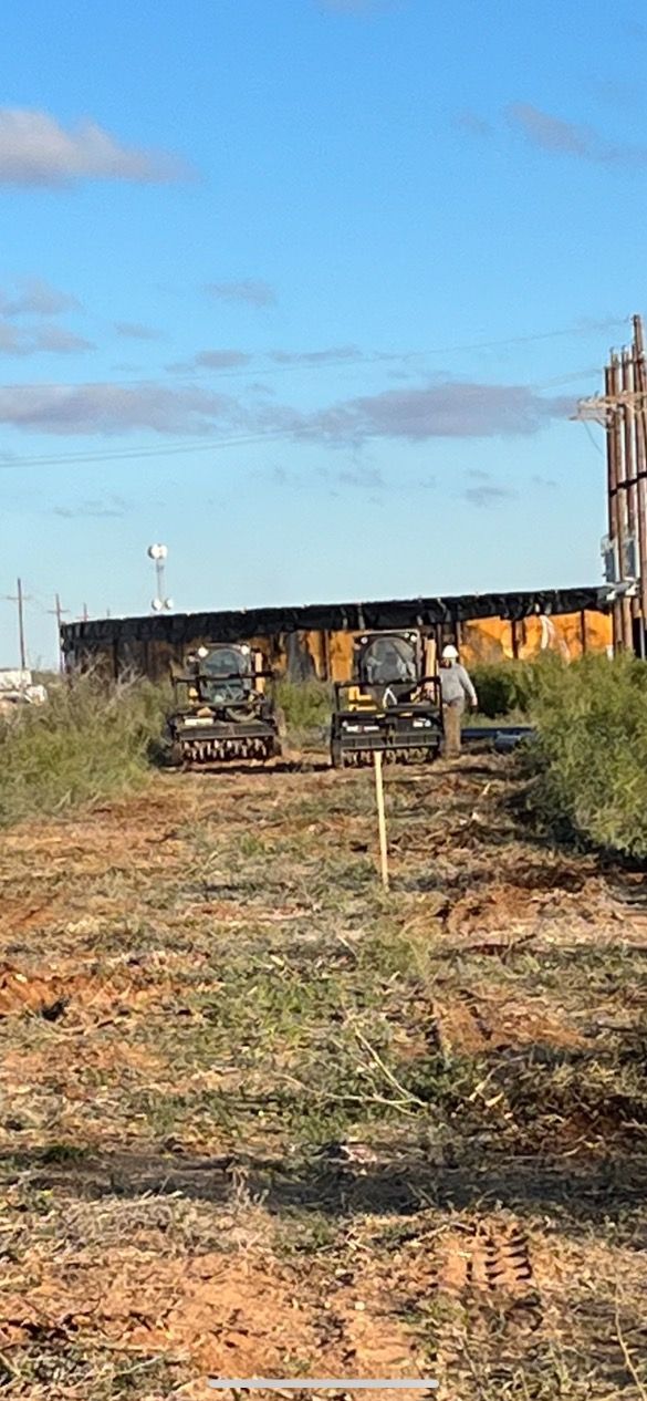 A couple of bulldozers are working on a dirt field.