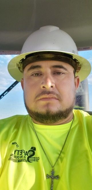 A man wearing a hard hat and a neon yellow shirt is sitting in a car.