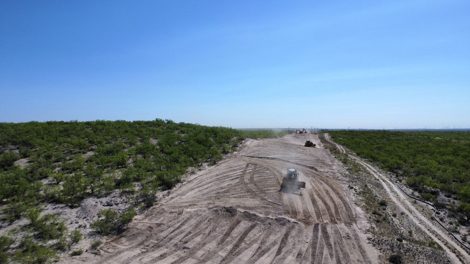 A group of cars are driving down a dirt road.