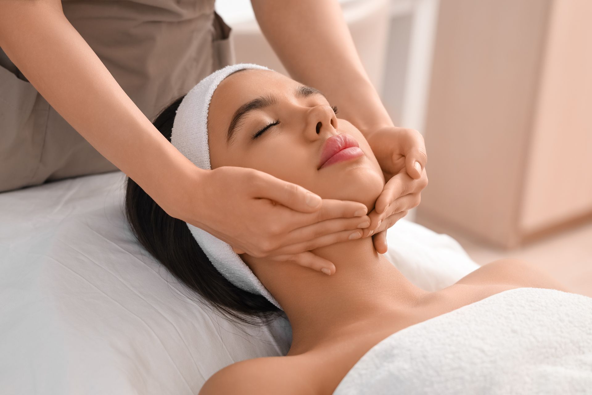 A woman is getting a facial massage at a spa.