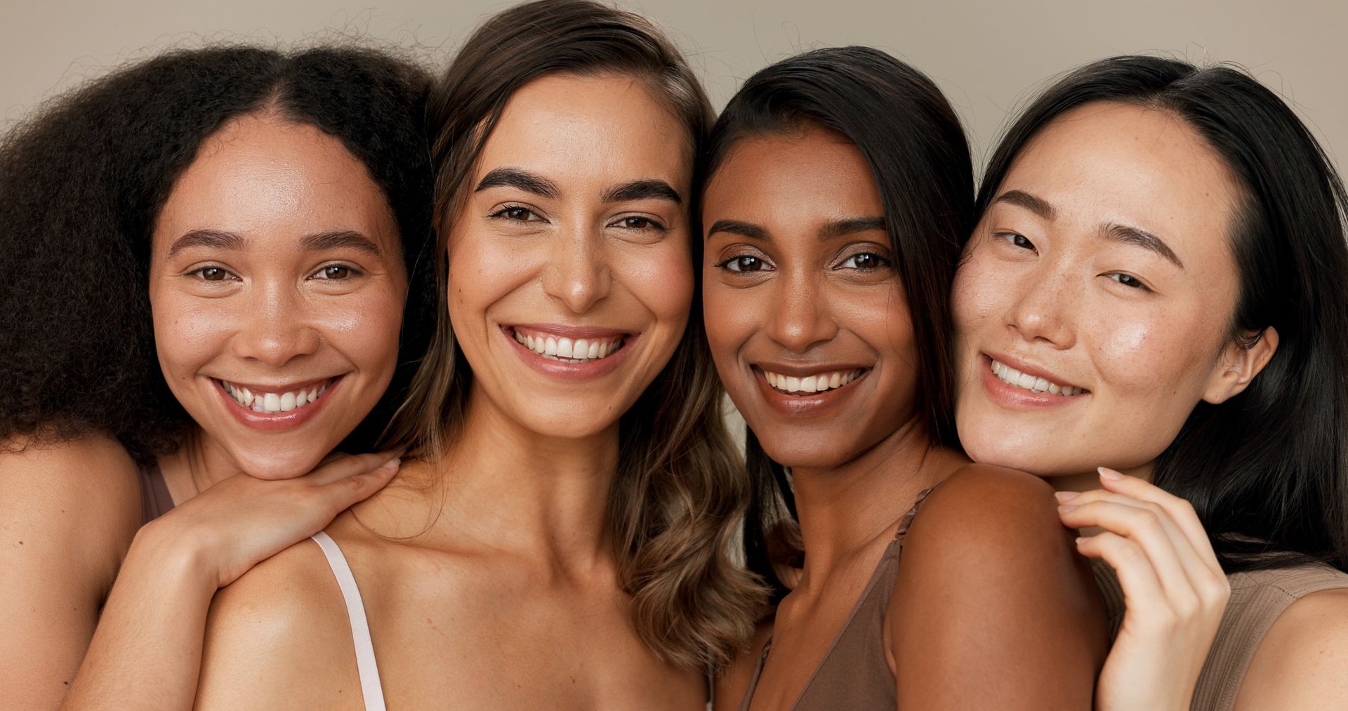 A group of women of different races are posing for a picture together and smiling.