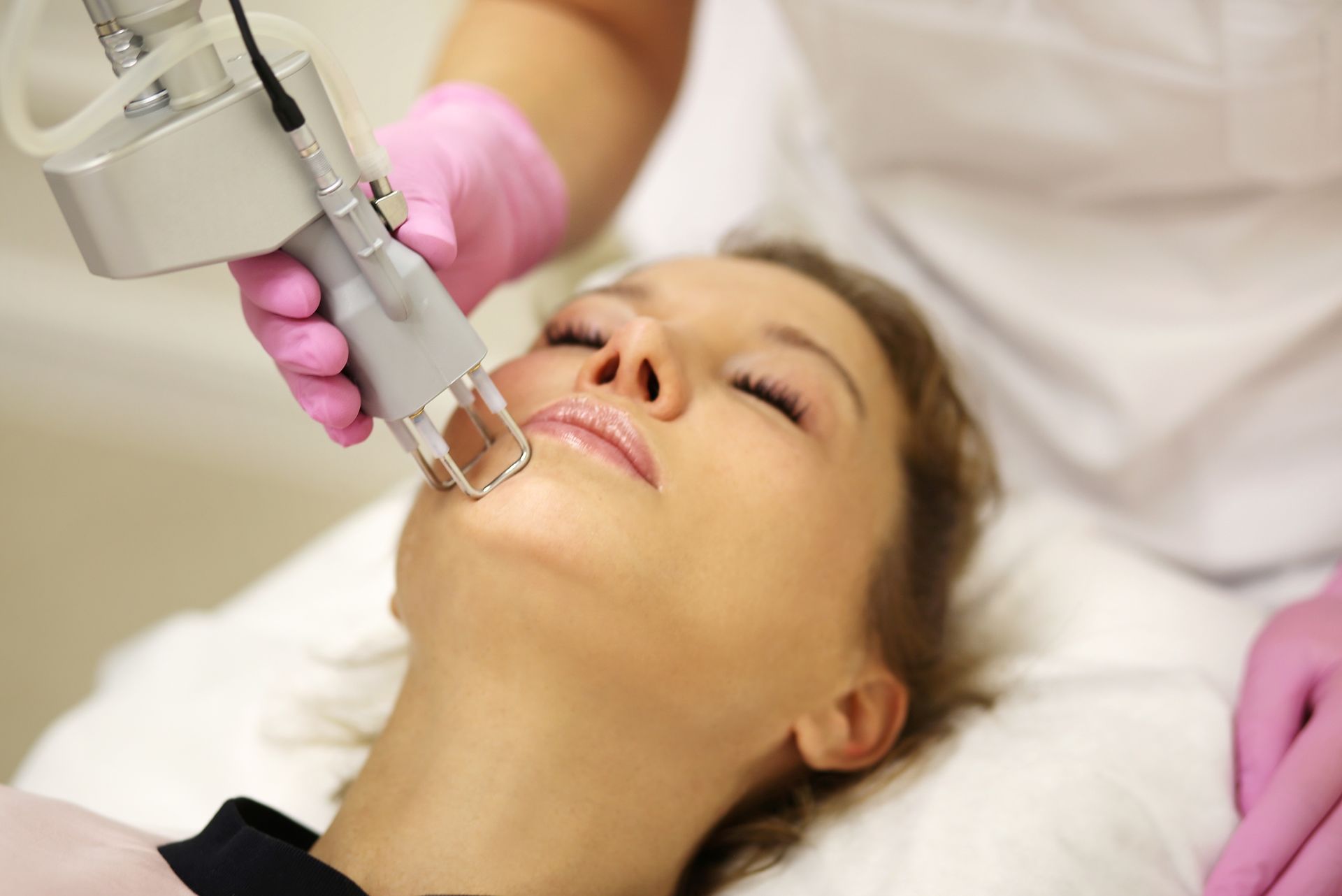 A woman is getting a laser treatment on her face.