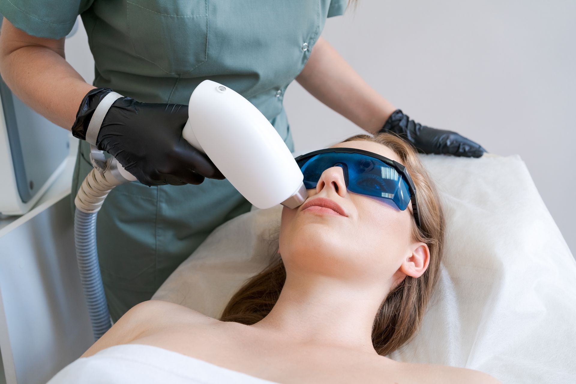 A woman is getting a laser hair removal treatment on her face.