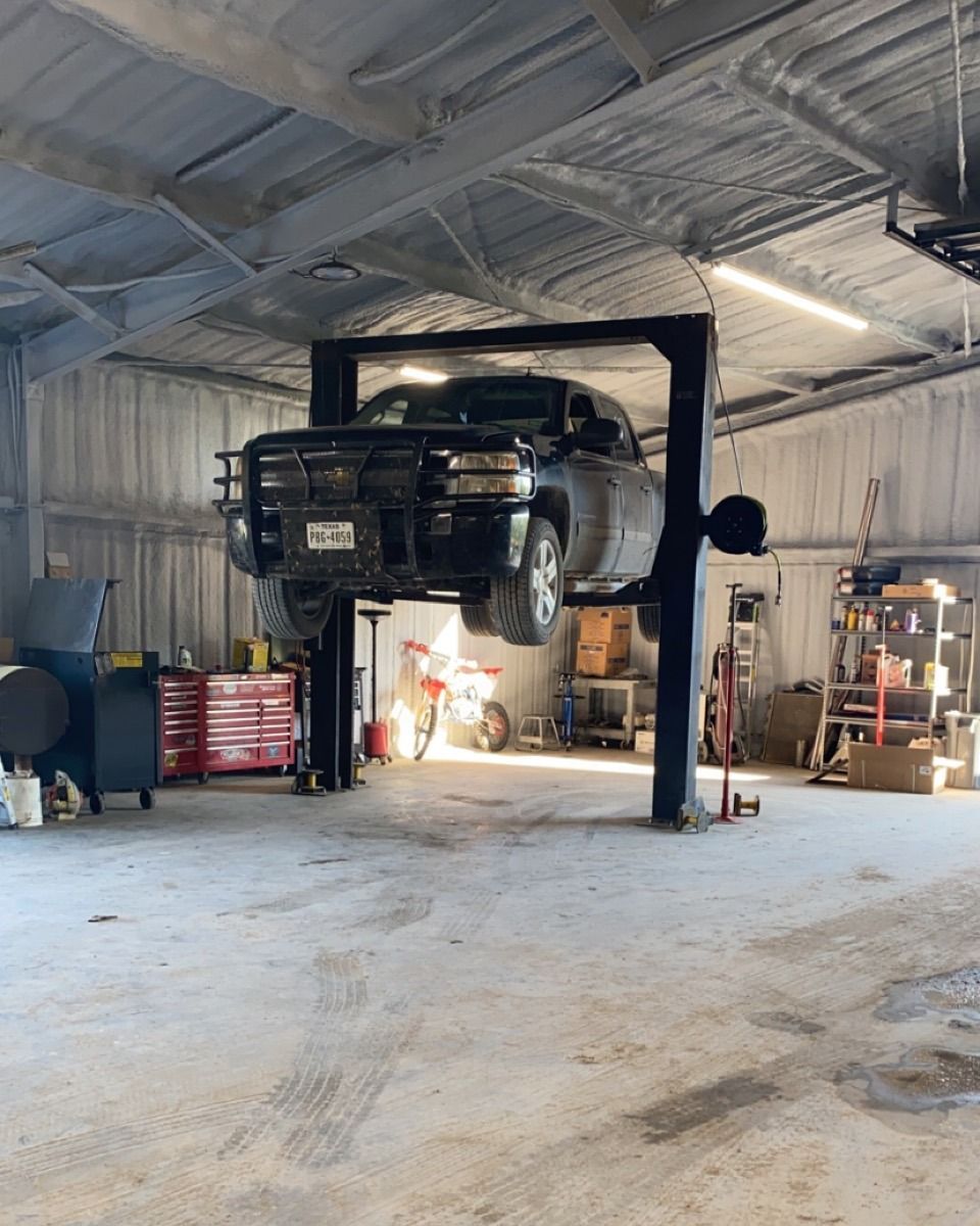 Truck raised on a lift in a garage with tools and equipment.
