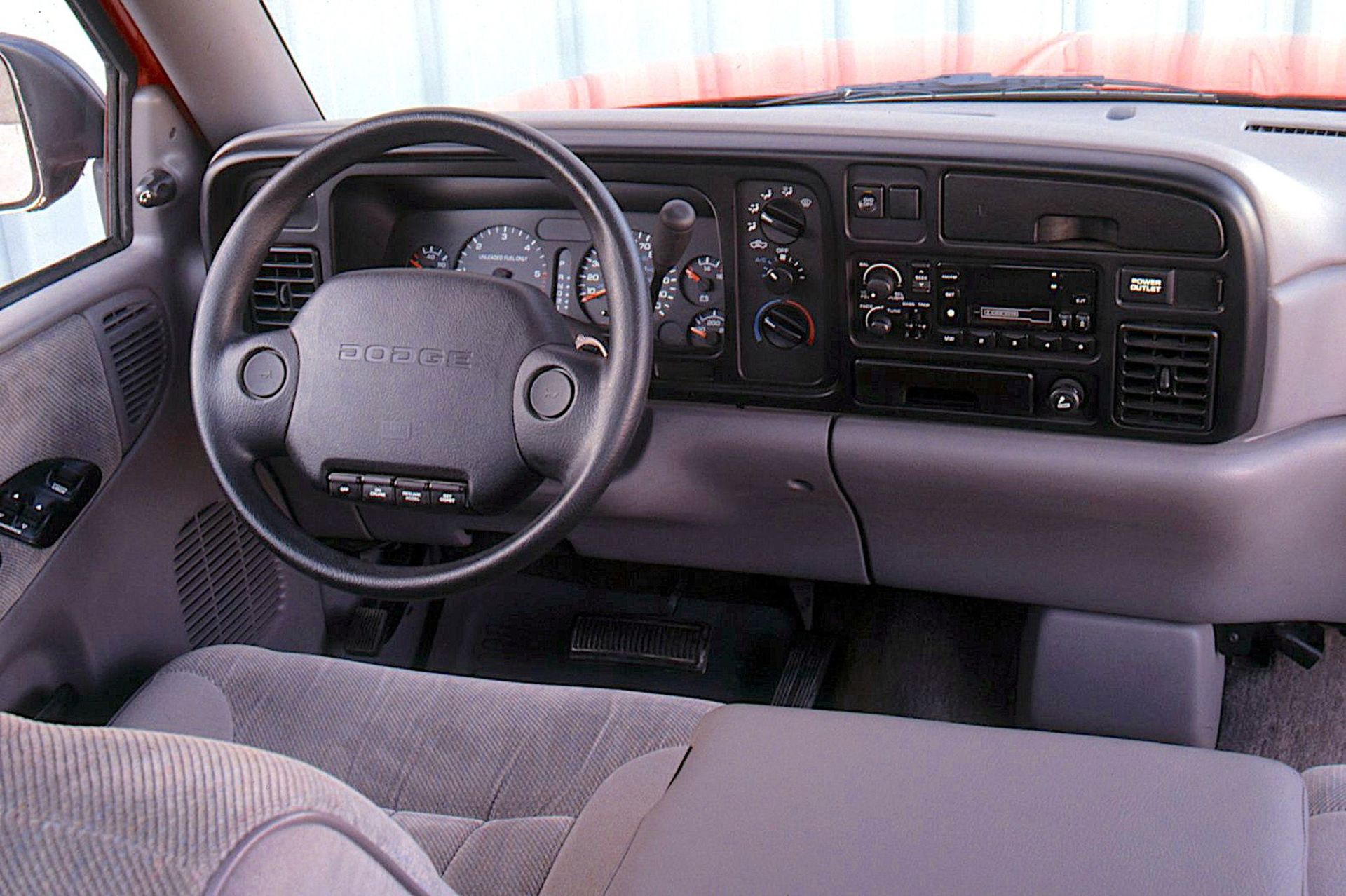 Interior of a gray Dodge pickup truck, featuring the dashboard, steering wheel, and seats.