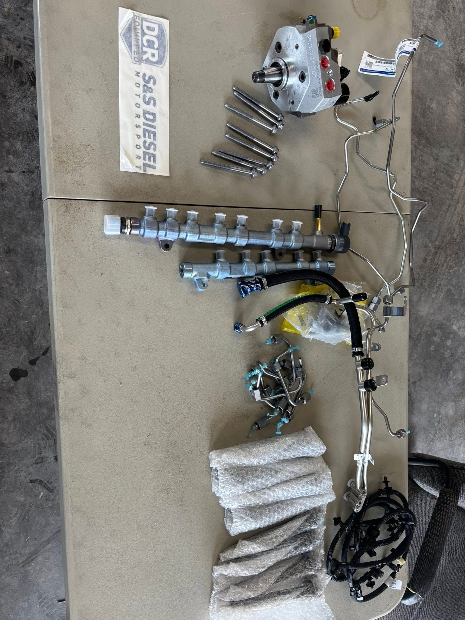 Diesel engine parts laid out on a table, including fuel lines, pump, and injectors.