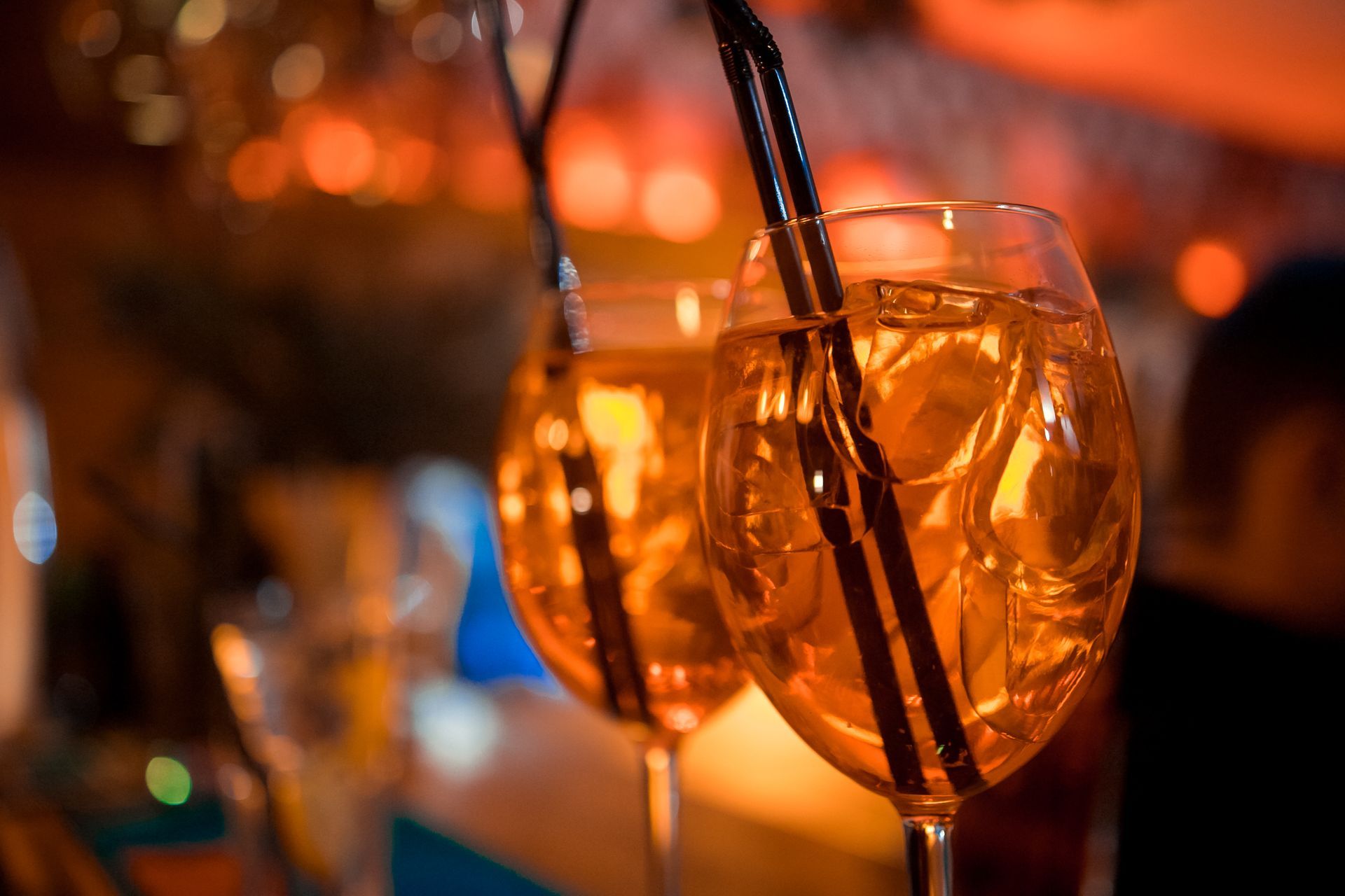 Due cocktail Aperol Spritz in bicchieri a calice con cannucce. Liquido arancione, ghiaccio, sfondo sfocato.
