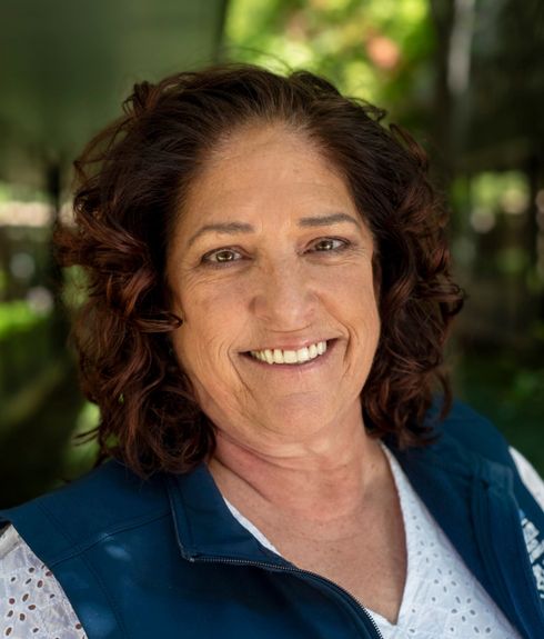 A woman wearing glasses and a white shirt is smiling for the camera.