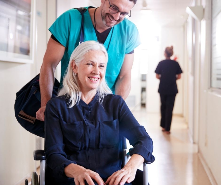 A smiling participant in a wheelchair being assisted during a hospital discharge, representing a successful transition of care managed by Plan and Grow in collaboration with NDIS Support Coordinators and discharge planners.