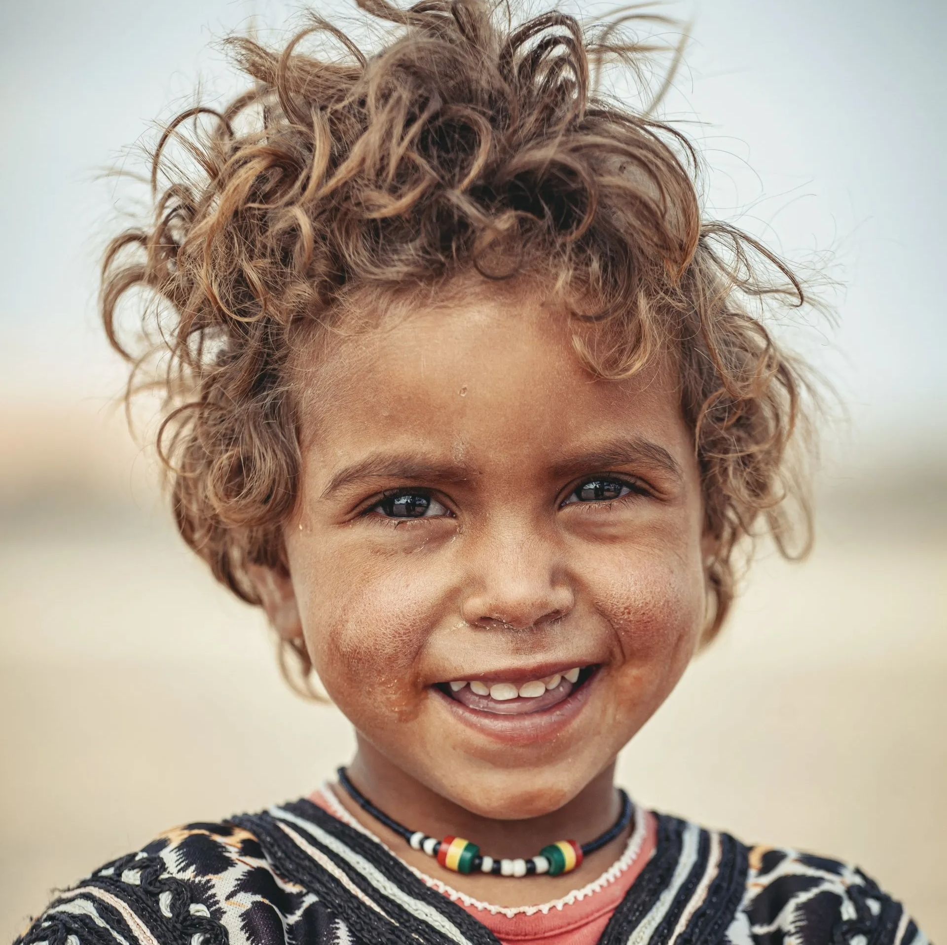 A young boy with curly hair is smiling for the camera.