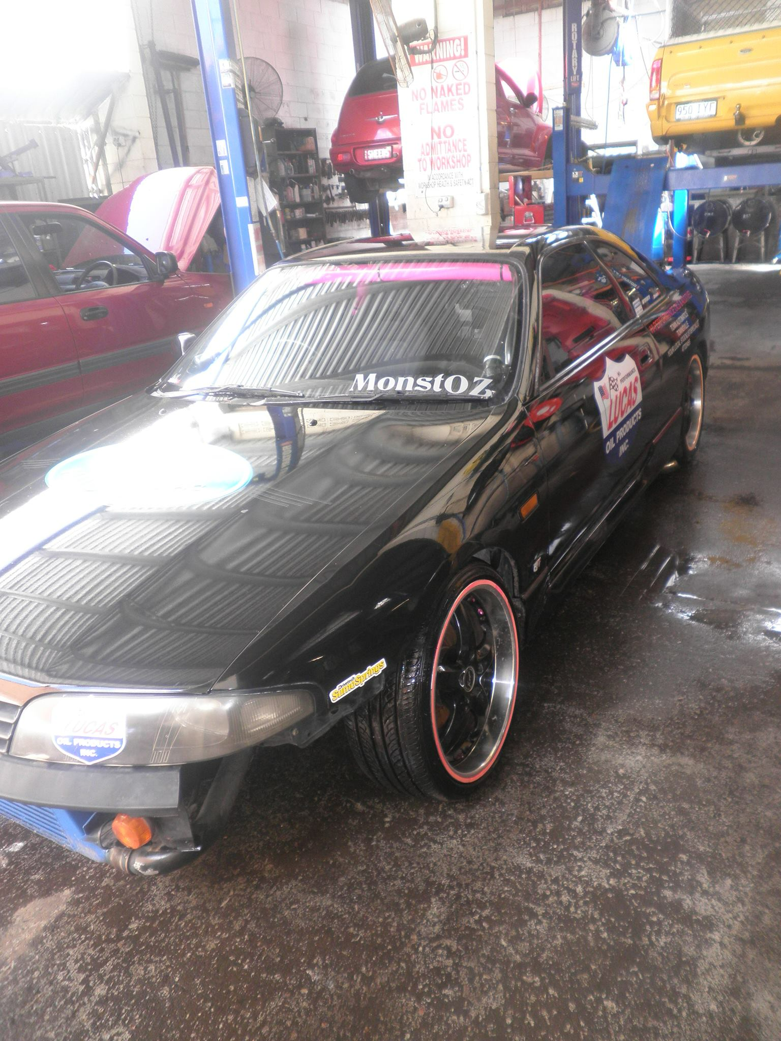 A Black Car With Red Rims Is Parked In A Garage — Town Automatics 4WD & Mechanical in South Townsville, QLD